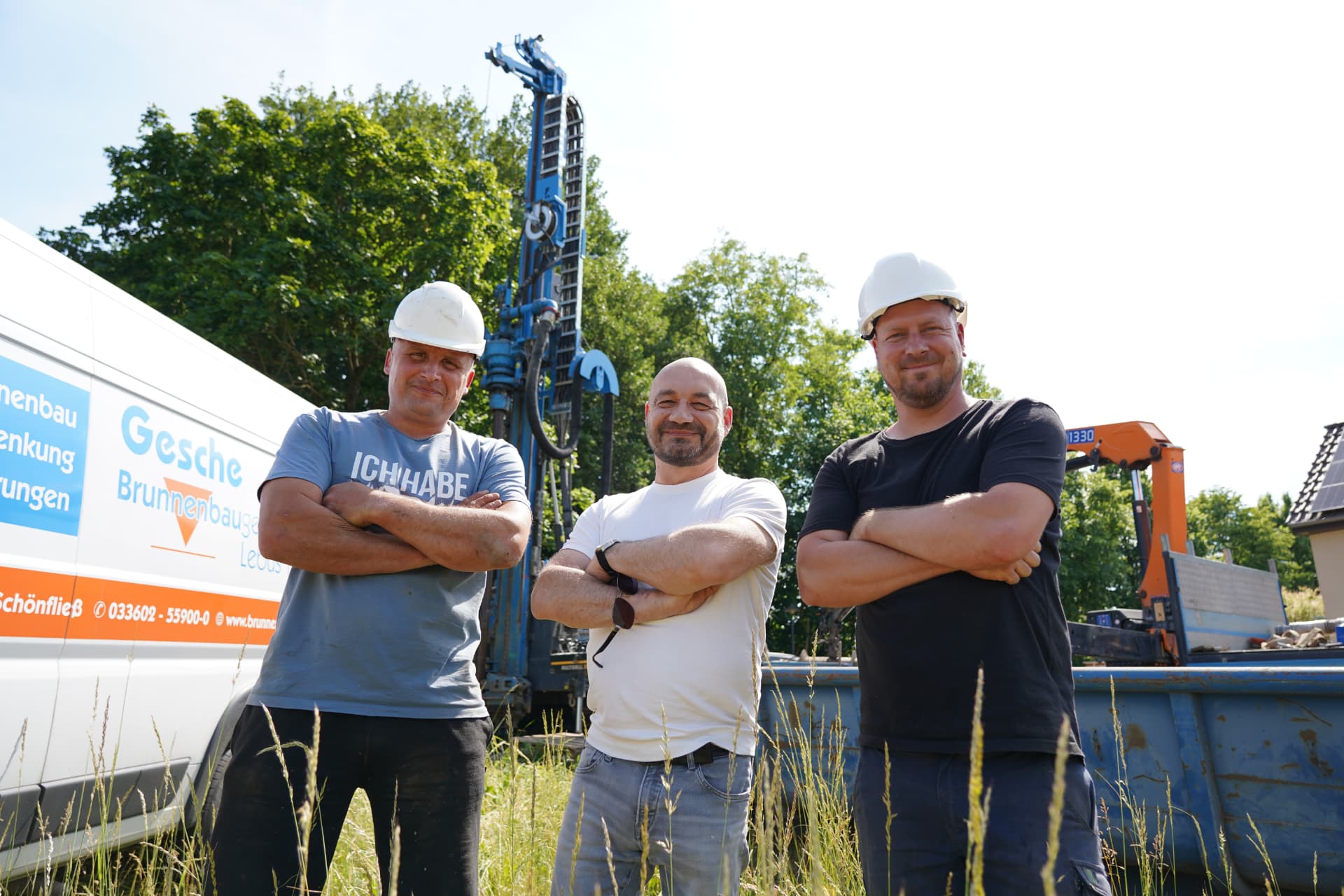 Drei Kollegen der Gesche-Brunnenbaugesellschaft Lebus vor Bohrgerät und Firmenfahrzeug auf einer Baustelle